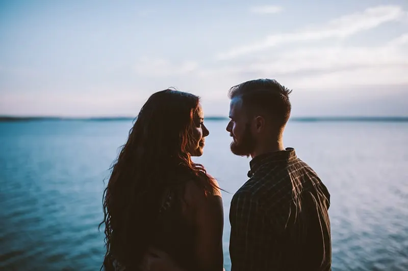 Eine Frau und ein Mann sehen sich an, während sie in der Nähe des Gewässers stehen