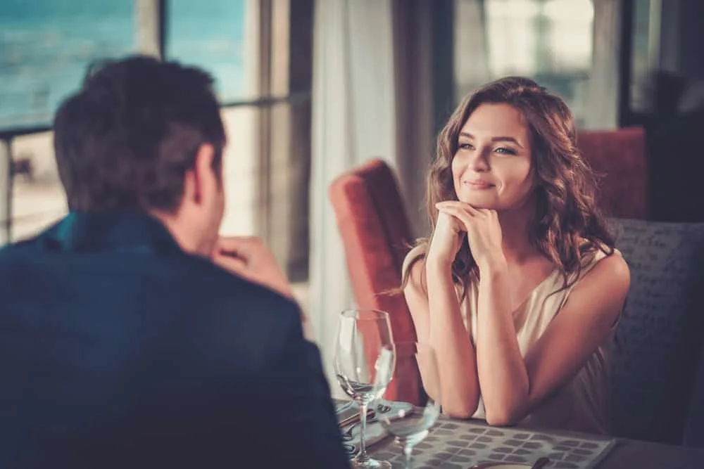 eine lächelnde Frau, die einen Mann an einem Datum im Restaurant ansieht