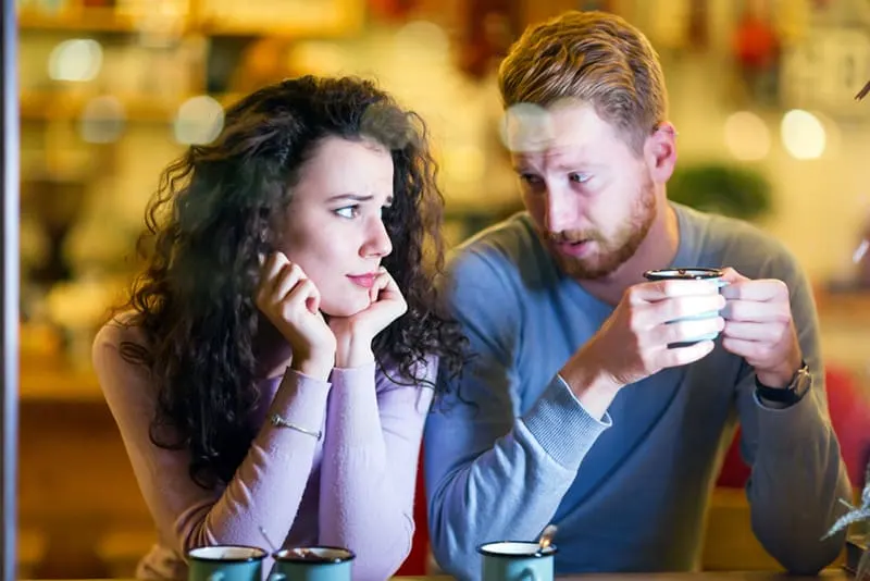 eine verwirrte Frau, die ihren Freund ansieht und mit ihr im Café spricht