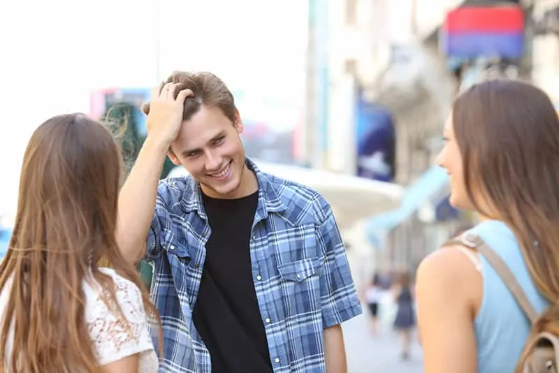 junger Mann flirtet mit zwei Frauen auf der Straße