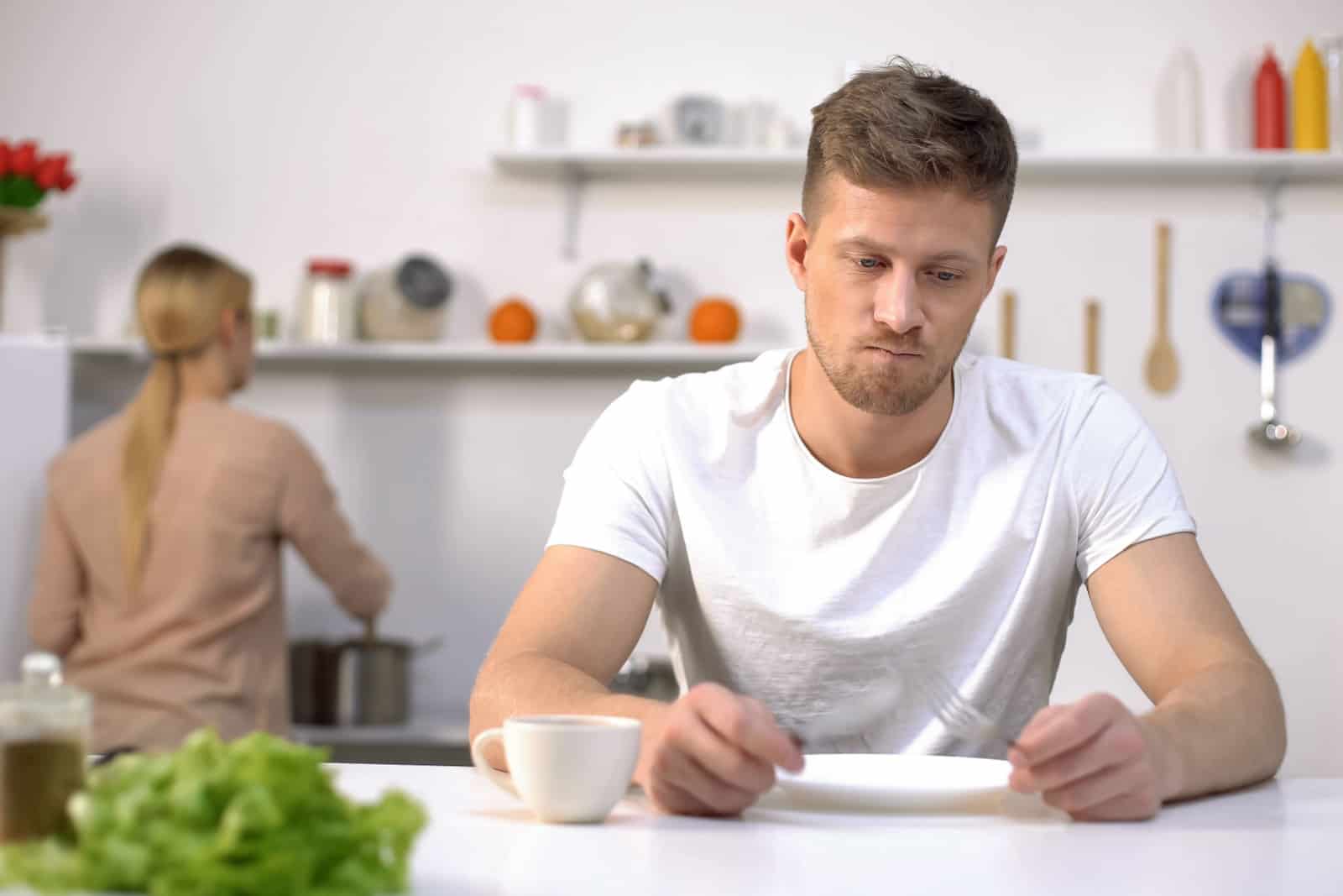 mann wartet auf frau, um ihm abendessen zuzubereiten