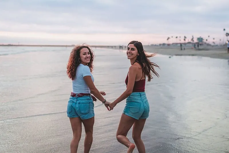 zwei Frauen Händchen haltend am Strand