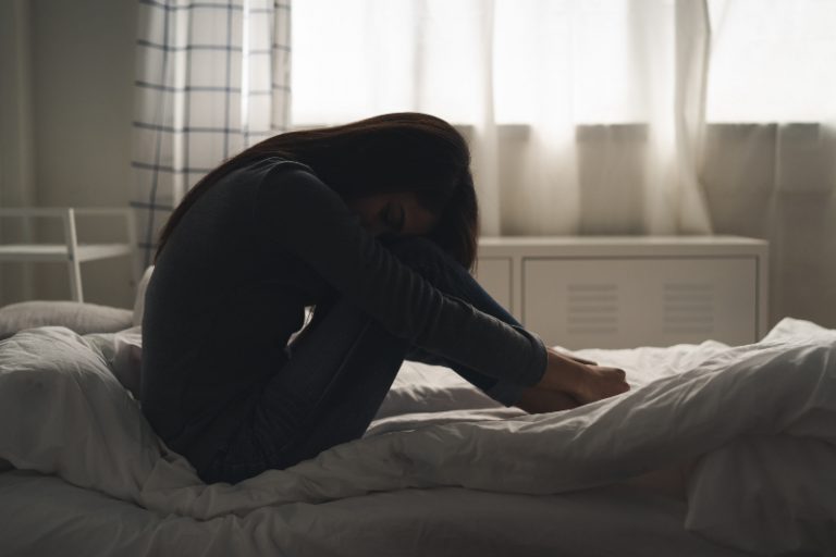 Ein Maedchen mit psychischen Problemen sitzt auf dem Bett
