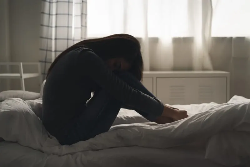 Ein Mädchen mit psychischen Problemen sitzt auf dem Bett