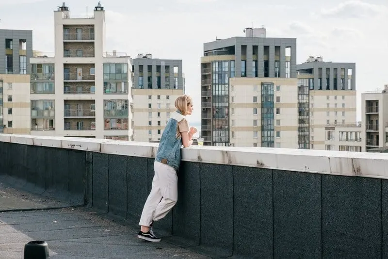 Die Blondine steht auf dem Dach des Gebäudes und beobachtet die Stadt