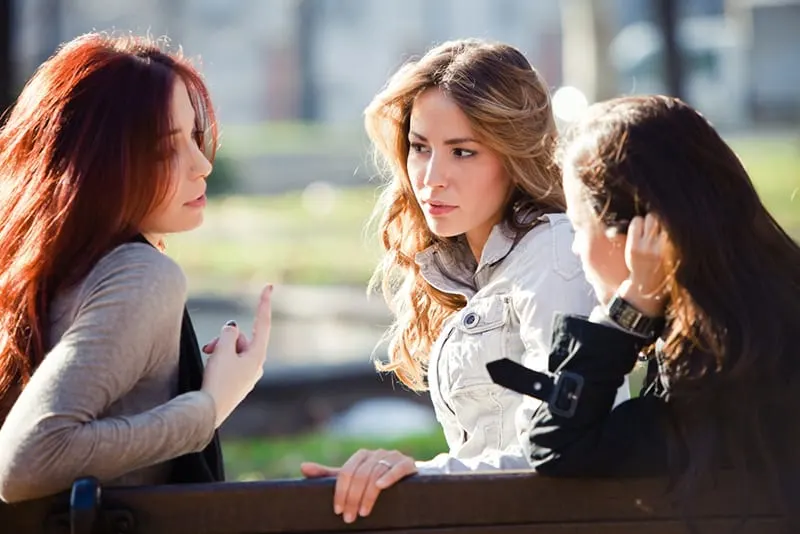 Drei Frauen sitzen auf der Bank und reden