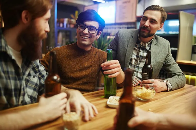 Drei Männer unterhalten sich in der Bar, während sie Bier trinken