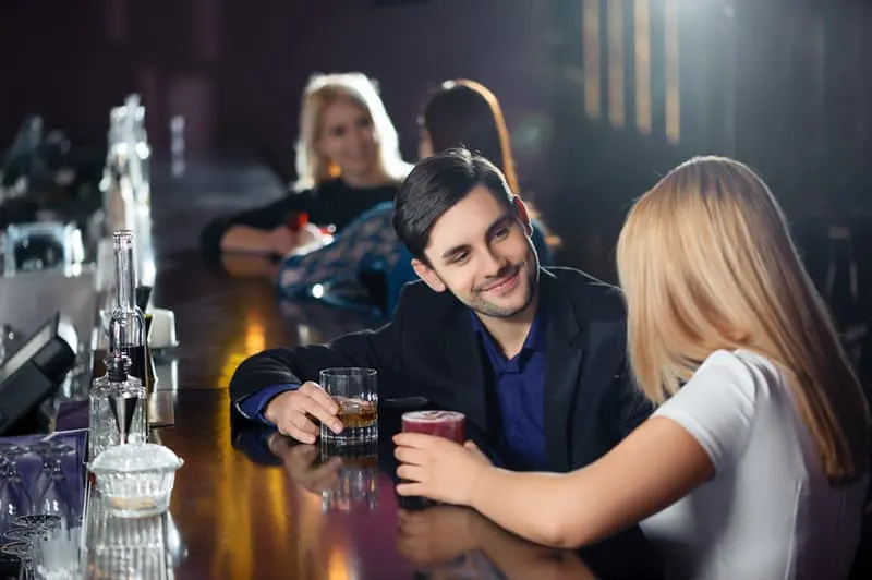 Ein Mann spricht mit einer Frau, während er an der Theke im Club sitzt