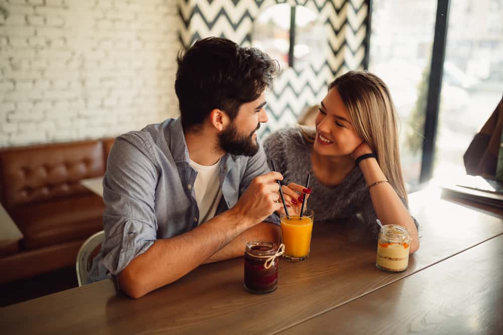 Ein Mann und eine Frau beobachten sich gegenseitig, während sie Saft trinken