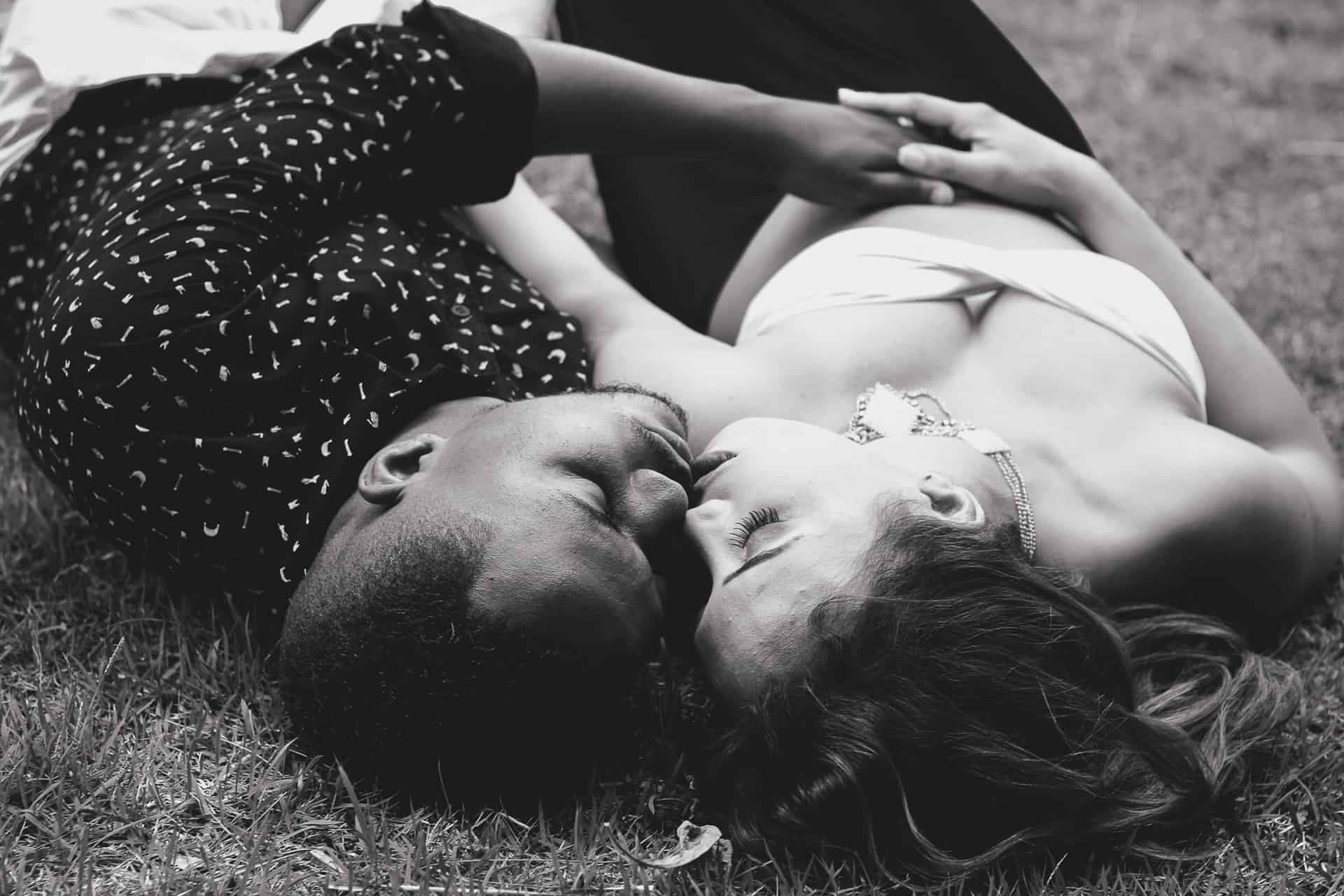 Ein Mann und eine Frau küssen sich, als sie im Gras liegen