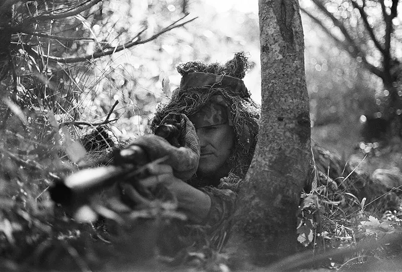 Ein Soldat mit einem Scharfschützen, der im Wald auf dem Boden liegt