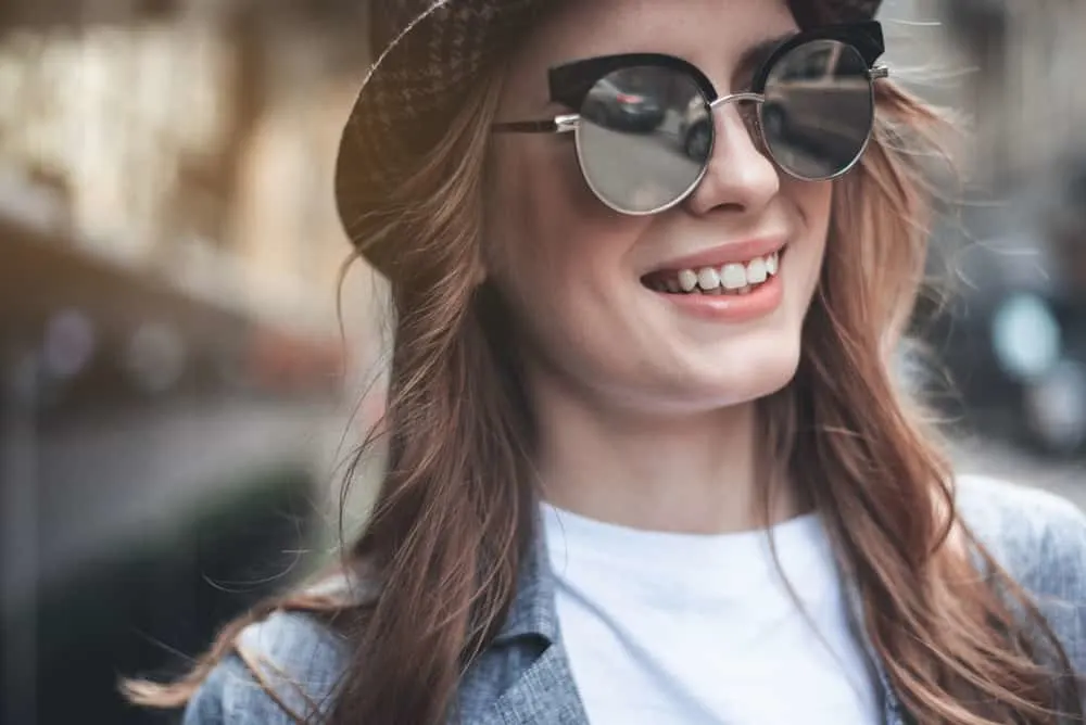 Eine Frau mit Brille und Hut lacht