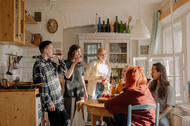 Eine Gruppe von Freunden trinkt Wein in der Küche und hängt ab