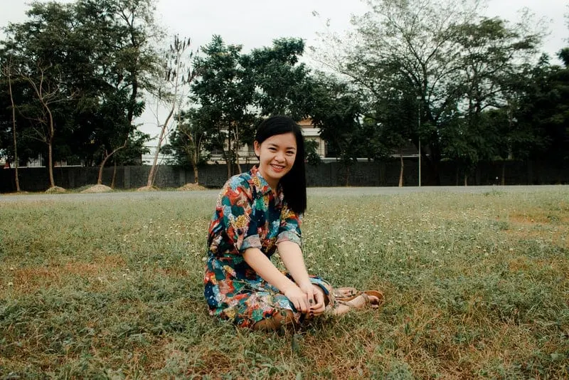 Eine lächelnde asiatische Frau sitzt im Gras