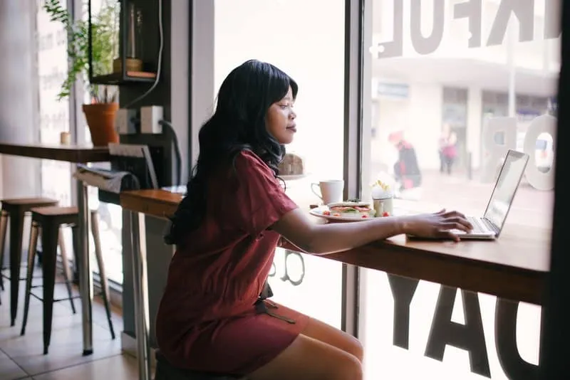 Eine schwarze Frau in einem Café benutzt einen Laptop