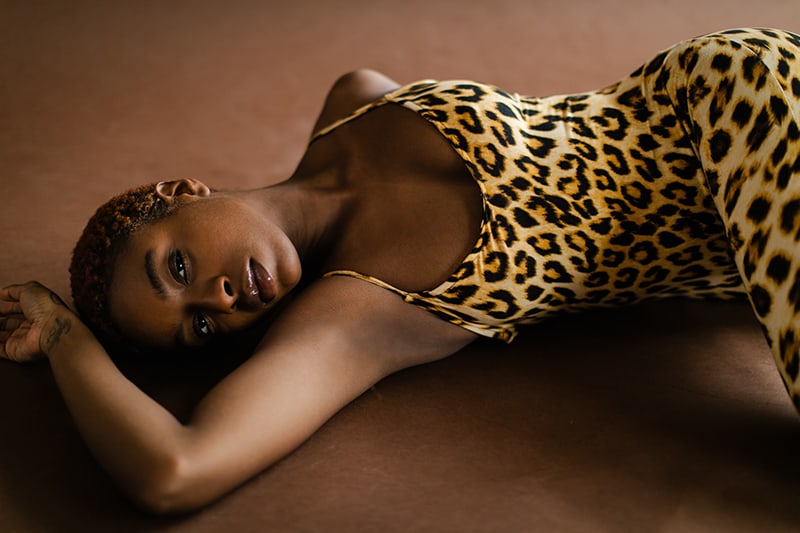 Frau im Overall mit Leopardenmuster, der auf dem Boden liegt und sexy aussieht