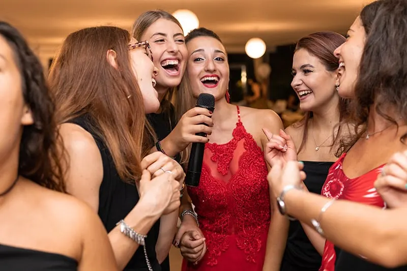 Gruppe von Freundinnen lacht, während einer von ihnen Mikrofon hält