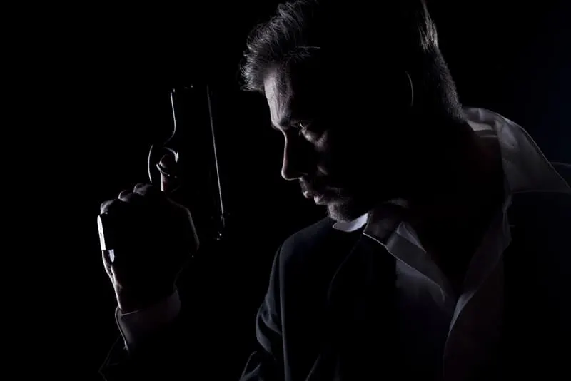 Männer Silhouette im Dunkeln mit einer Waffe in der Hand