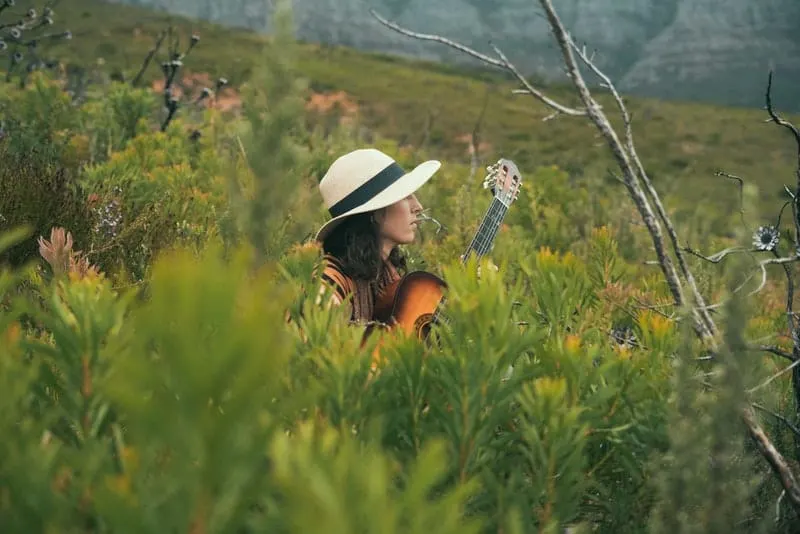 Im hohen Gras spielt eine Frau Gitarre