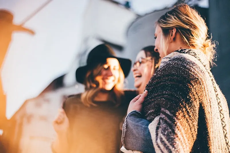 Drei Frauen lachen und reden draußen