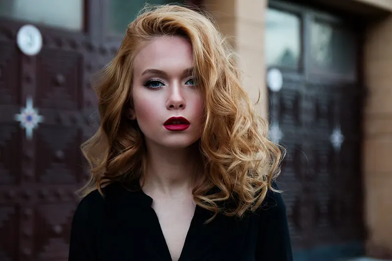 eine blonde Frau mit rotem Lippenstift, die vor dem Gebäude steht