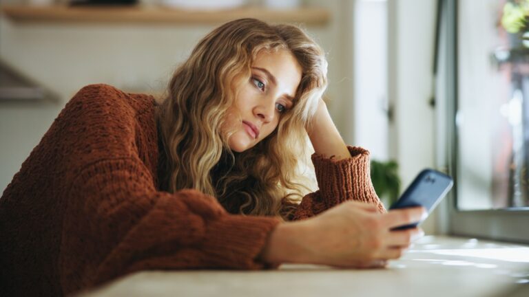 frau sieht traurig aufs handy