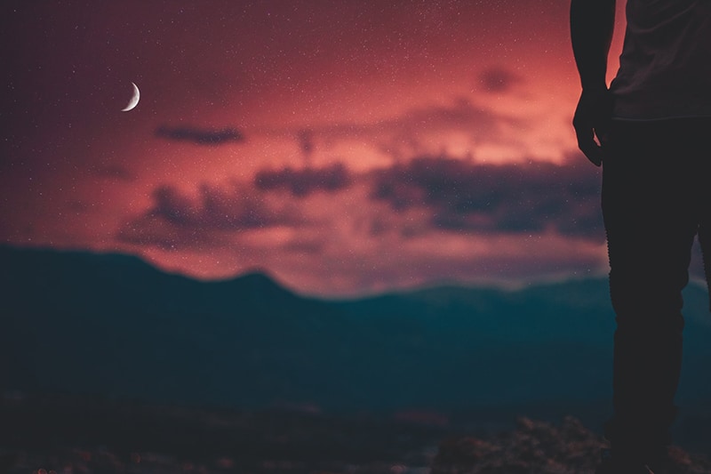 Silhouette eines Mannes, der den Mond betrachtet, während er allein steht