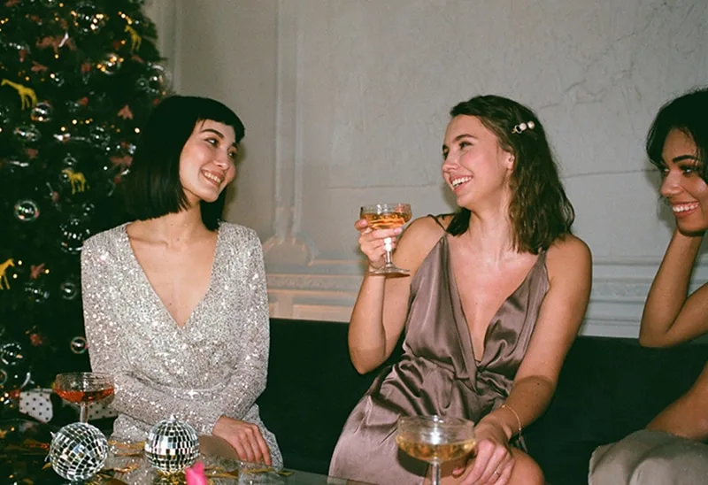Drei lächelnde Frauen sitzen auf der Couch auf der Party