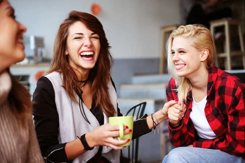 Drei Frauen lachen zusammen im Cafe