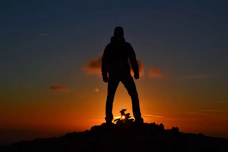 ein Mann, der auf einem Hügel bei Sonnenuntergang steht