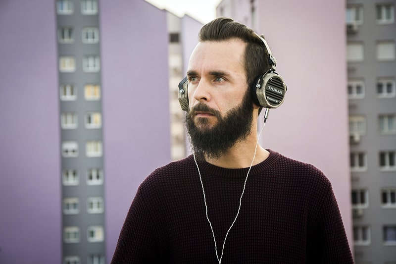 Ein Mann mit Kopfhörern, der Musik hört, während er draußen steht