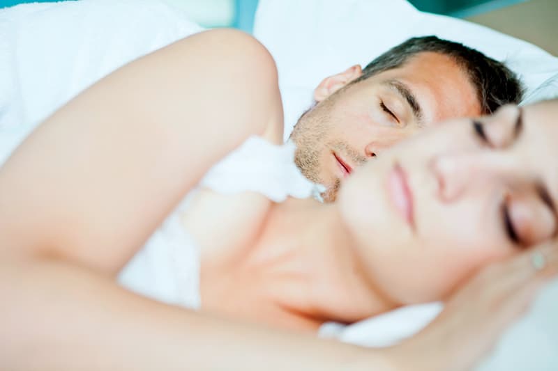 Ein Paar schläft in einem Bett mit weißen Laken