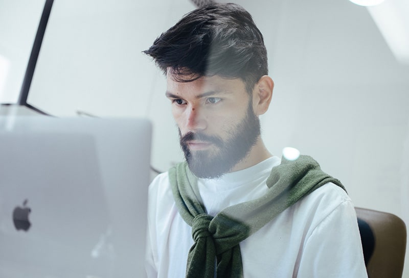 ein fleißiger Mann, der einen Laptop betrachtet, während er im Büro sitzt