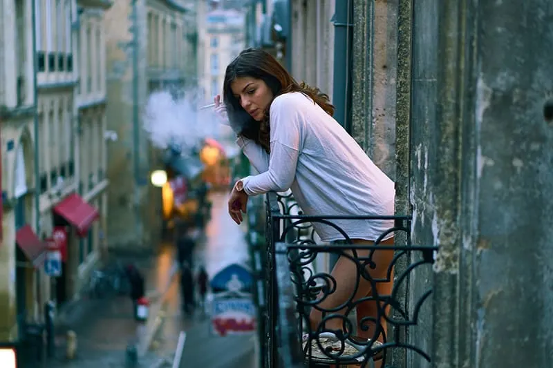eine Frau, die auf dem Balkon eine Zigarette raucht