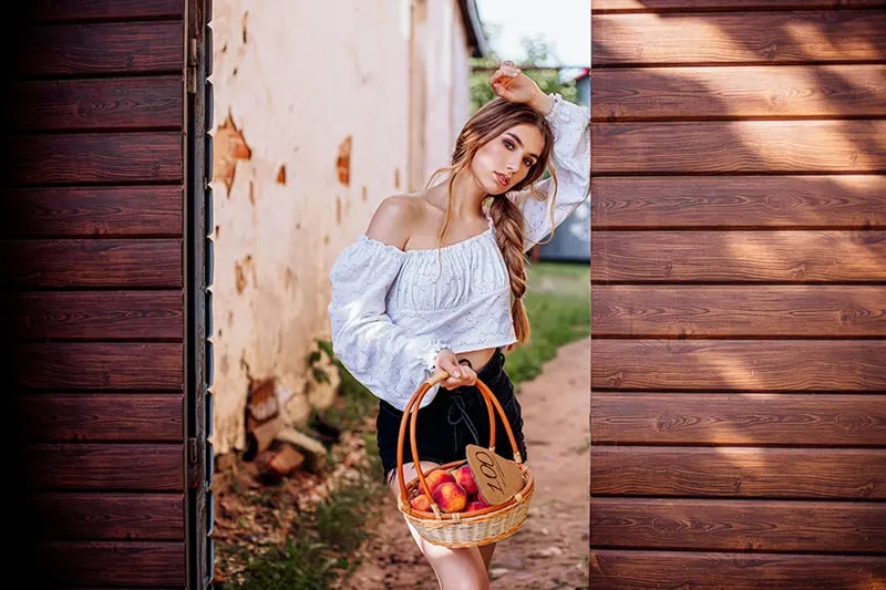 eine Frau, die einen Korb mit Pfirsichen hält, während sie auf dem Tor steht