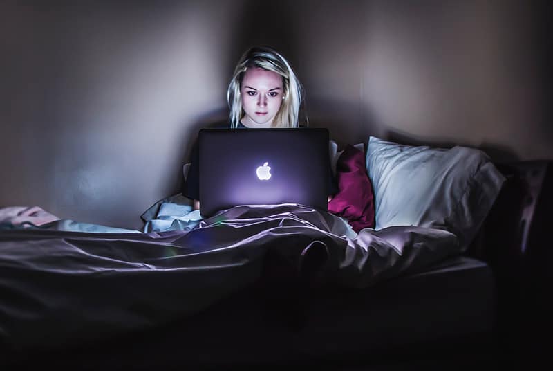 Eine Frau, die einen Laptop in einem Bett benutzt, bleibt lange wach