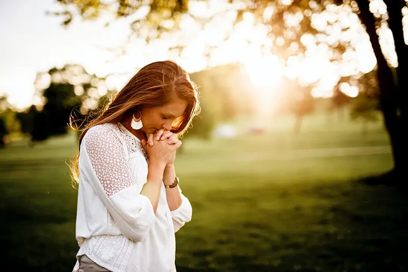 eine Frau, die neben einem Baum im Park betet