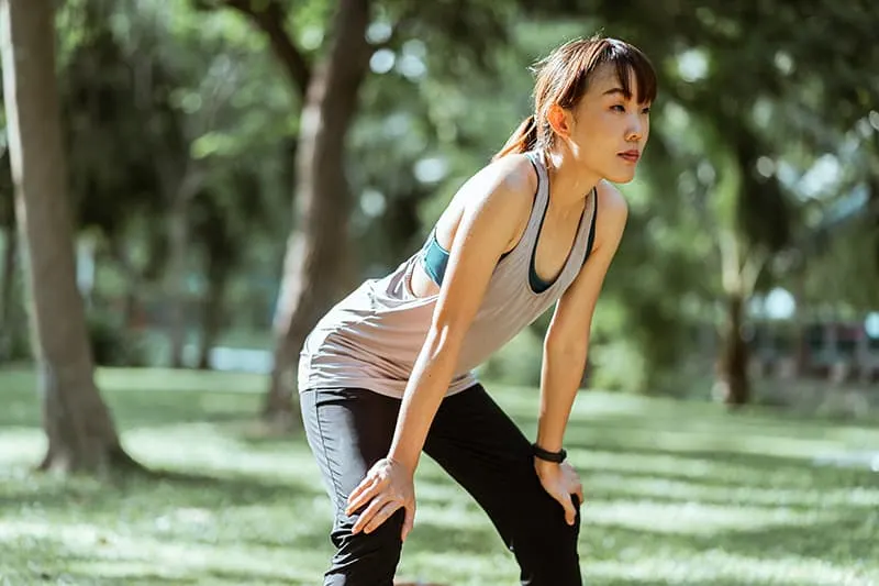 eine Frau, die sich nach einem Training in einem Park ausruht