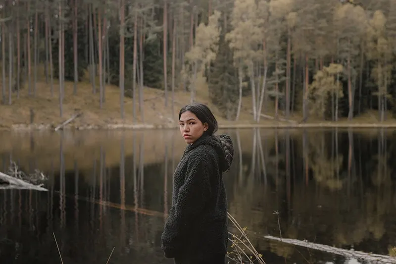 eine Frau, die in der Nähe des Sees im Wald steht