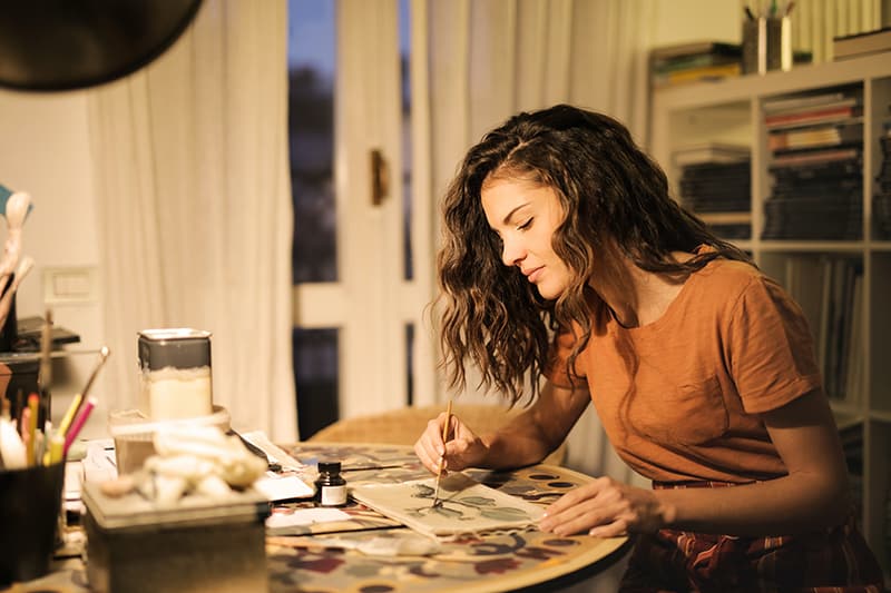 eine Frau, die in ihrem Atelier auf Papier malt
