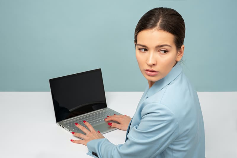 eine Frau, die einen Laptop benutzt und über die Schulter schaut