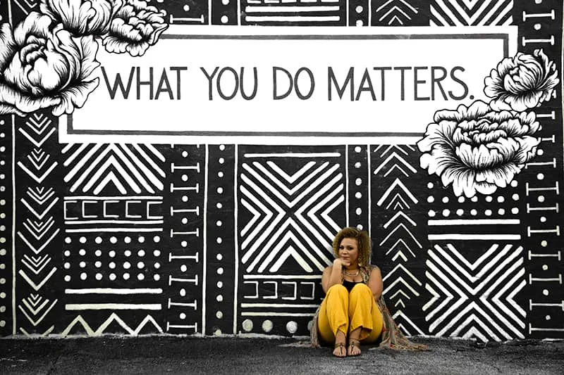eine Frau, die auf dem Boden nahe der Graffitiwand sitzt