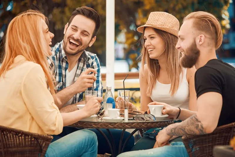 Eine Gruppe von Freunden lacht und scherzt, während sie im Café sitzen