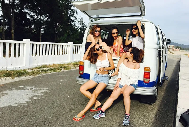 eine Gruppe von Freundinnen, die im Kofferraum des Autos sitzen und zusammen lachen