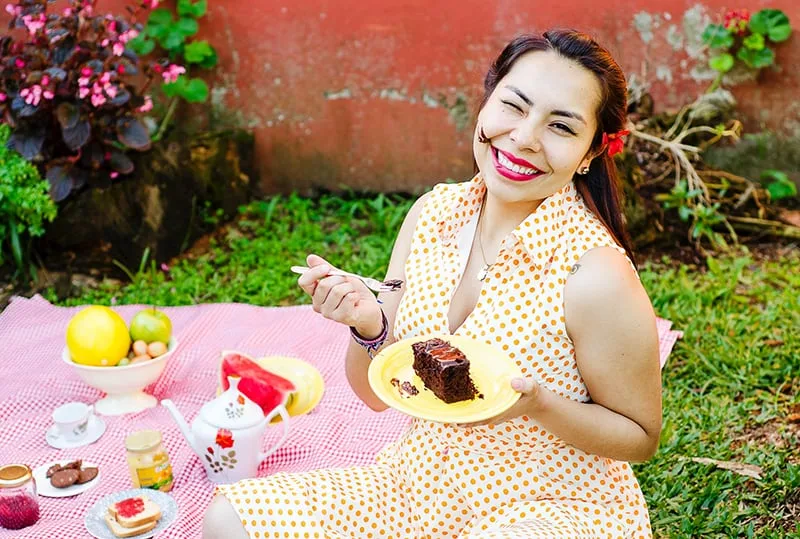 eine lächelnde Frau, die einen Kuchen auf einem Picknick isst