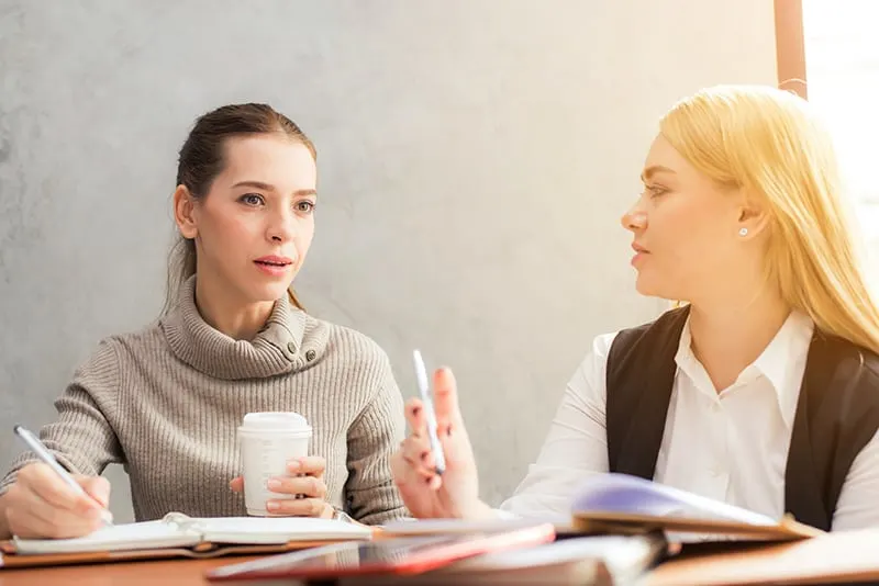 Zwei Frauen unterhalten sich und diskutieren über die Arbeit im Büro