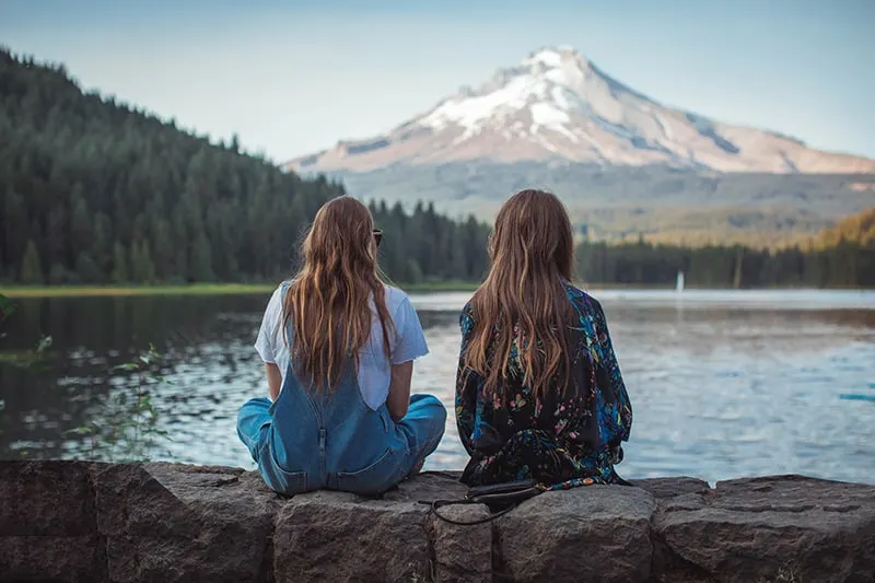 Zwei Frauen sitzen auf dem Felsen und blicken auf den See
