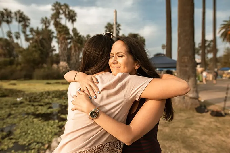 zwei Frauen umarmen sich, während sie im Park stehen