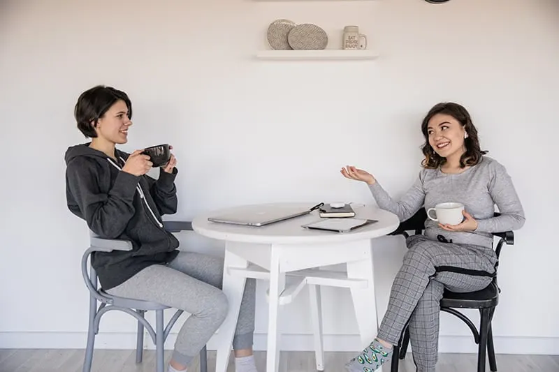 Zwei Frauen unterhalten sich, während sie zusammen Tee trinken und am Tisch sitzen