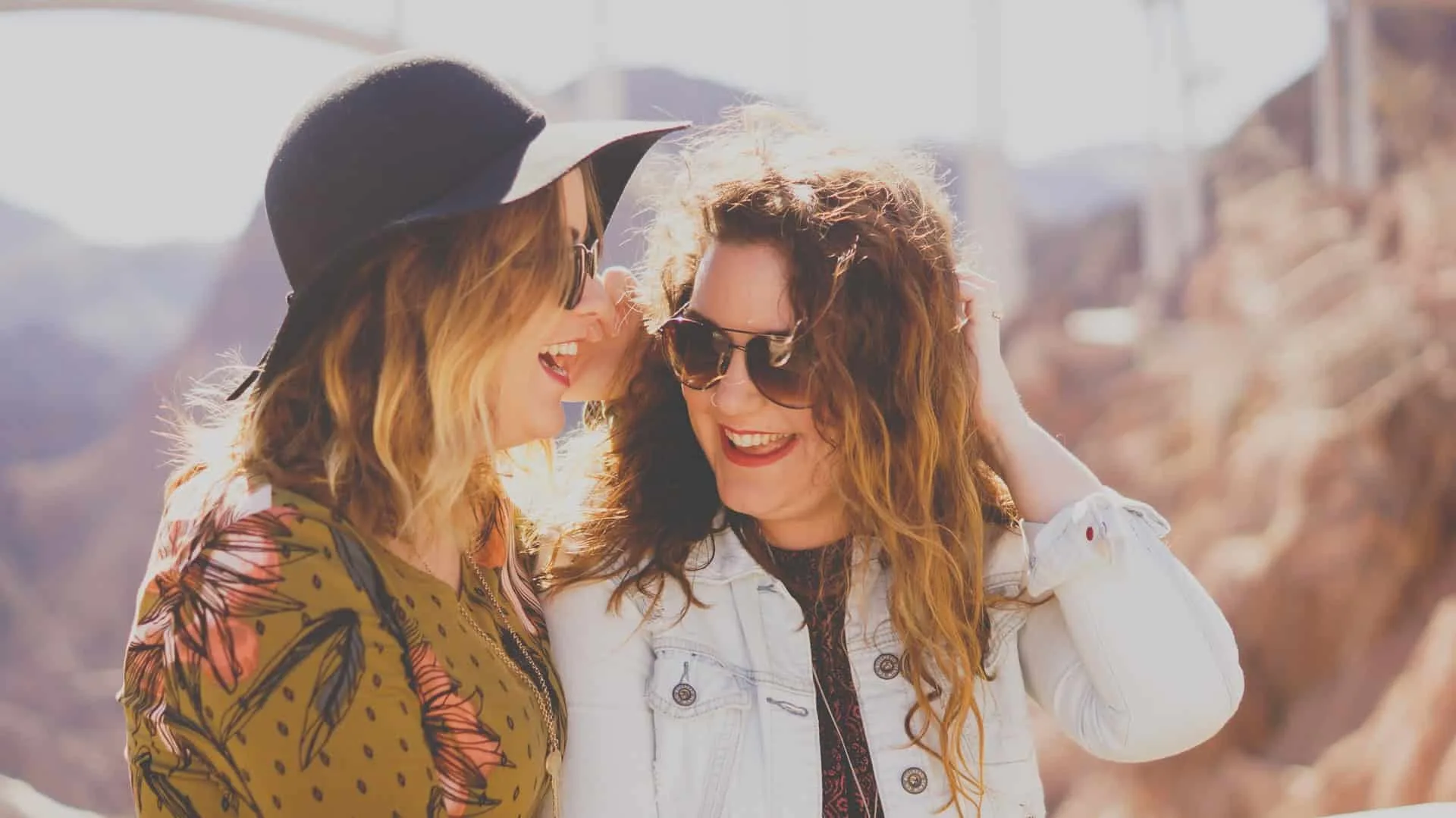 zwei Freundinnen lachen zusammen, während sie draußen stehen
